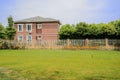 Grassy lawn before fenced house in sunny summer