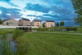 Grassy park with pond bridge trees and bench in front of multi storey homes