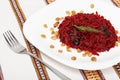 Grated beet salad with prunes and raisins, served on a white plate and home tablecloth