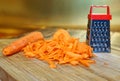 Grated carrot lies on a wooden cutting board on a golden background. Unusual mystery and optical illusion