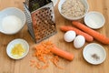 Grated carrots, ground almonds, eggs and spices, baking ingredients on a wooden kitchen board for an Easter carrot cake Royalty Free Stock Photo