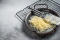 Grated cheese for cooking in a steel tray with grater. White background. Top view. copy space Royalty Free Stock Photo