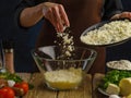 Grated cheese in a glass bowl in frozen flight on a dark background. Vegetables, herbs, eggs, spices on a wooden table. A