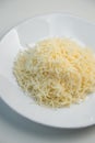 Grated cheese on a white plate close-up. Grated cheese salad, restaurant serving of the dish Royalty Free Stock Photo