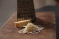 Grated italian parmesan cheese on wooden chopping board with a block of parmasan and a grater in the background. Close up photo Royalty Free Stock Photo
