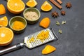 Grated orange peel on grater. Sliced orange and spices on table