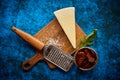 Grated parmesan cheese and metal classic grater placed on wooden cutting board Royalty Free Stock Photo