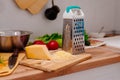 Woman rubs parmesan cheese on a grater.