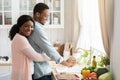 Grateful African Wife Cuddling Husband From The Back While He Washing Dishes