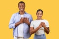 Grateful black couple holding hands on heart