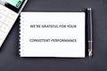 A grateful message emphasizing consistent performance is placed on a notepad next to a calculator and a pen, reflecting