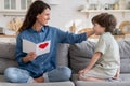 Grateful mom touch cute kid son hair hold postcard with greetings on mother day sit on couch at home