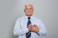 Grateful senior man with hands on chest against grey background Royalty Free Stock Photo