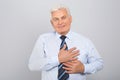 Grateful senior man with hands on chest against grey background Royalty Free Stock Photo