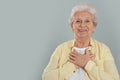 Grateful senior woman with hands on chest against background. Space for text