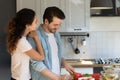 Grateful wife embracing shoulder of husband engaged in preparing salad