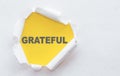 Grateful word written on yellow background under torn white paper