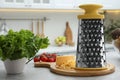 Grater, cheese and vegetables on table in kitchen Royalty Free Stock Photo