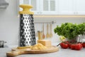 Grater, cheese and vegetables on table in kitchen Royalty Free Stock Photo