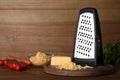 Grater, cheese and vegetables on wooden table. Space for text Royalty Free Stock Photo