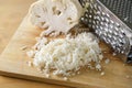 Grating cauliflower with a metal grater on a wooden kitchen board, used as rice replacement for a healthy low carb or ketogenic Royalty Free Stock Photo