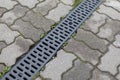 Grating of drainage system rainwater in the park at the sidewalk from a stone shaped paving slabs. Landscaped a city Royalty Free Stock Photo