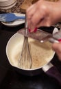 Grating nutmeg over bechamel sauce in a pan at home kitchen. Royalty Free Stock Photo