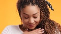 Young grateful african american woman feeling thankfulness, touching her chest and smiling, orange studio background