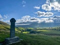 Grave with the Celtic cross monument in the field under a blu sky