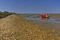 Gravel beach with fishing boat and tidal mudflats