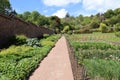 A gravel path runs alongside the unusual stepped effect of the wall of a kitchen garden at an English stately house near Tiverton