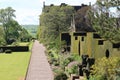 A gravel path runs between a clipped hedge and a well manicured lawn in the grounds of an English country house