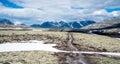 Gravel pathway used as leading lines towards mountain scenery with snow capped mountains and blue sky.