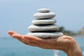 Gravel pile in woman's hands with sea background