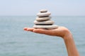 Gravel pile in woman's hands with sea background