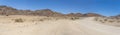 gravel road and Dolerite boulder buttes in desert, near Hobas, Namibia