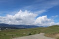 Gravel road through grass fields and hills