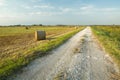 Gravel road and hay bales on the field, tiny clouds on the sky Royalty Free Stock Photo