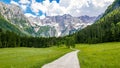 Beautiful alpine valley, gravel road, green meadows surrounded by mountains. Jezersko, Slovenia. Royalty Free Stock Photo