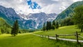 Beautiful alpine valley, gravel road, green meadows surrounded by mountains. Jezersko, Slovenia. Royalty Free Stock Photo