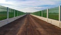 The gravel road lies between the white cement fence