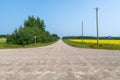 Gravel roads intersect near a field of Canola in rural Alberta, Canada