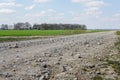 Gravel rural road along a green field against a blue sky Royalty Free Stock Photo