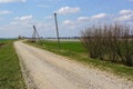 Gravel rural road along a green field against a blue sky Royalty Free Stock Photo