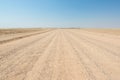 Gravel straight road crossing the colorful Namib desert, in the majestic Namib Naukluft National Park, best travel destination in Royalty Free Stock Photo