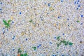 Gravel texture of white, yellow, blue natural stone rubble, green grass plants Royalty Free Stock Photo