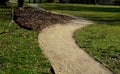 Gravel threshing path in city park light sand green lawn and trees trunks slight bend plain Royalty Free Stock Photo