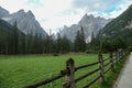 A gravelled road leading along a lush green meadow, secured with a wooden fence, leading to Italian Dolomites. Royalty Free Stock Photo