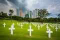 Graves and modern buildings in the distance at the Manila American Cemetery & Memorial, in Taguig, Metro Manila, The Philippines.