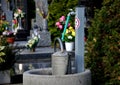 Between the graves is a tap with water for watering flowers in the cemetery. the stainless steel device protrudes from a circular